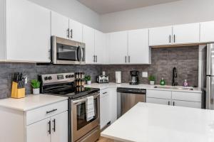 una cucina con armadietti bianchi ed elettrodomestici in acciaio inossidabile di 2BR Luxury New Apartment with Outdoor Pool a Kansas City