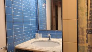 La salle de bains est pourvue de carrelage bleu, d'un lavabo et d'un miroir. dans l'établissement A Nicaredda, à Cefalù