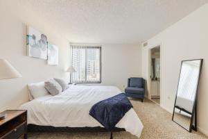 1 dormitorio con 1 cama blanca y 1 silla azul en 2BR Serene Executive Retreat with Balcony en Arlington