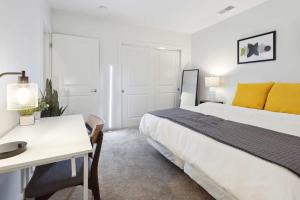 a white bedroom with a large bed and a desk at 2BR Executive Downtown Apartment in Detroit
