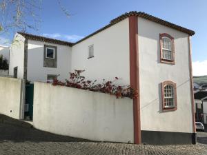a white house with red flowers on a wall at Apartamento acolhedor no centro da cidade, com pátio privado. in Angra do Heroísmo +15 photos