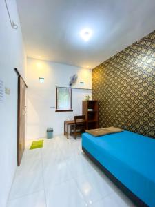 a bedroom with a blue bed and a desk at Nitha Homestay in Banyuwangi