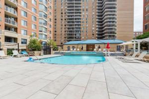 an outdoor swimming pool with chairs and tables and buildings at 2BR Luxury City Suite With Gym & Pool in Arlington