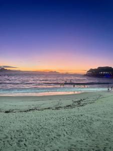 a group of people on the beach at sunset at Namastê House Copacabana in Rio de Janeiro