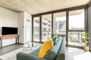 a living room with a blue couch and large windows at 2BR Chic New Apartment With Rooftop Pool & Gym in Chicago