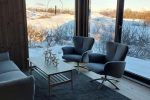 um quarto com três cadeiras, uma mesa e uma grande janela em Cabin Aurora Borealis em Sommarøy