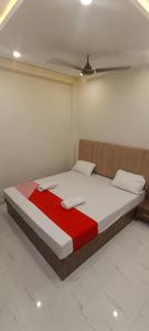 een bed in een kamer met een rood en wit dekbed bij Goroomgo BNK Grand Varanasi - Ganga River 100m in Varanasi