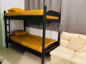 a couple of bunk beds in a room with a couch at Hotel Adventure Lodge in Jacó