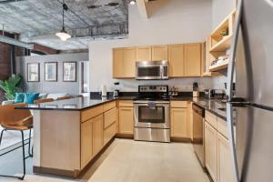 a kitchen with wooden cabinets and a stainless steel refrigerator at 2BR Historic Loft Retreat With Pool & Gym in Pittsburgh