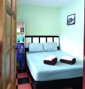 1 dormitorio con 1 cama con 2 almohadas en D'TERRACE KUNDASANG, en Ranau