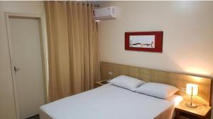 una camera con un letto bianco e una foto a parete di Flat DiRoma. a Rio Quente