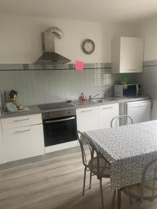 une cuisine avec des placards blancs et une table avec des chaises dans l'établissement Maison individuelle a Arreau, à Arreau