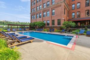 une piscine avec des chaises longues et un bâtiment dans l'établissement 2BR 2BA Historic Loft Retreat With Pool, à Pittsburgh