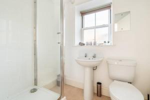 Baño blanco con aseo y lavamanos en Retreat in Axminster: Your Getaway near Devon en Axminster