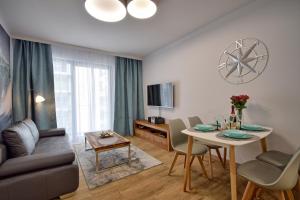 a living room with a couch and a table with chairs at Piękny Apartament Balticus SeaView by Rent like home in Międzyzdroje
