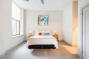 a white bedroom with a bed and two windows at 2BR Distinguished Apartment Rooftop Deck & Gym in Baltimore