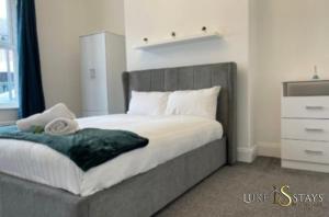 a bedroom with a large bed with a gray headboard at Luke Stays - Nicholson Terrace in Killingworth