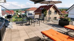 un patio con mesa, sillas y sombrilla en Alpenblick 