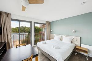 a bedroom with a bed and a table and a balcony at All Suites Appart Hôtel - Bassin d'Arcachon - Dune du Pilat in La Teste-de-Buch