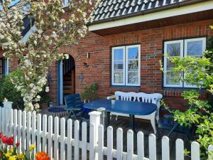 a white picket fence with a blue table in front of a house at Ferienwohnung-J-Jacobs in Wrixum