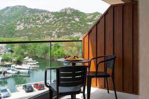 a table and chairs on a balcony with a view of a river at Hotel De‘Andros Virpazar in Virpazar