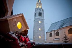 un campanile della chiesa con una torre dell'orologio sullo sfondo di Casa Viola a Cortina dʼAmpezzo