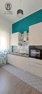 une cuisine avec des placards blancs et un mur bleu dans l'établissement La Terra di Cerere, à Trapani