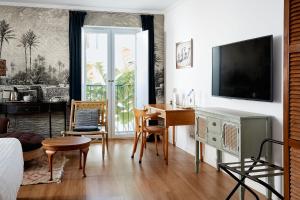 a bedroom with a table and a desk with a television at Casa Apollo Guesthouse in Faro