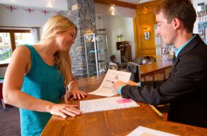 a man and a woman sitting at a table signing papers at Hôtel Club mmv Le Val Cenis *** in Lanslebourg-Mont-Cenis +42 photos