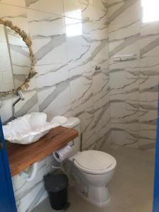 a bathroom with a toilet and a marble wall at Villa Coral azul in Prado
