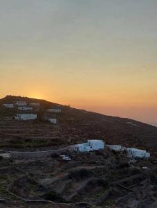 una puesta de sol sobre un campo con casas en una colina en Seascape, apartment 1 with sea view en Ano Meria