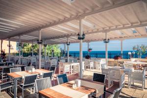 un restaurante al aire libre con mesas y sillas y el océano en Tiva del Mar Beach Hotel, en Sveti Vlas