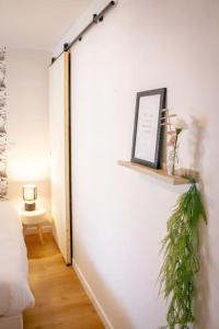 a room with a white wall with a plant on a shelf at Le douillet : Duplex élégant en Centre ville in Albertville +11 photos