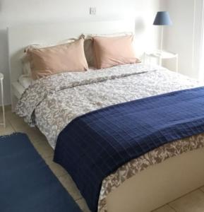 a bed with a blue blanket and pink pillows at Katikies 14 Beach Villa in Pissouri
