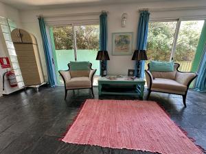 een woonkamer met 2 stoelen en een rood tapijt bij Hotel Donatella mare boutique in Punta del Este