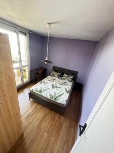 1 dormitorio con cama y pared púrpura en Chambre artistique entre Disneyland et Paris en Neuilly-sur-Marne