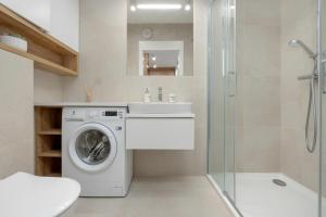 a bathroom with a washing machine and a sink at Przytulny apartament Perła Bałtyku in Rogowo