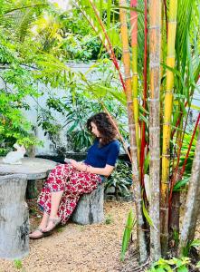 a woman sitting on a bench in a garden at B&B Shenal Villa Kosgoda in Kosgoda