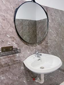 um lavatório de casa de banho com um espelho redondo na parede em Neko Homestay Hue em Hue