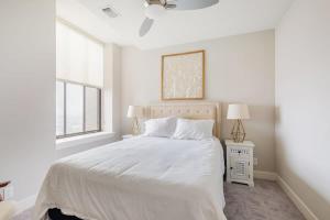 a white bedroom with a bed and two windows at 2B 2BA Distinguished Apartment Rooftop Pool & Gym in Baltimore