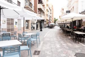 an empty street with tables and chairs and umbrellas at Apartamento Don Algodón Grau in Los Mártires