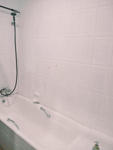 a white bath tub with a shower in a bathroom at Be Our Guest Near OR TAMBO International Airport Room 2 in Boksburg