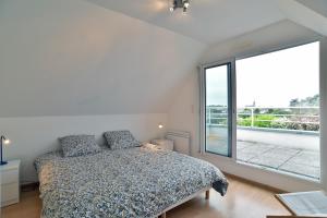 a bedroom with a bed and a large window at La Villa des Marettes - Piscine partagée in Pléneuf-Val-André
