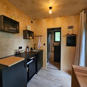 una cocina con encimera negra y fregadero en Tiny House La Clairière au milieu des bois ! en Sonchamp