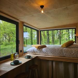 1 dormitorio con cama y ventana grande en Tiny House La Clairière au milieu des bois ! en Sonchamp