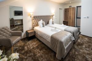 um quarto de hotel com duas camas e uma cadeira em ALIVE HOTEL em Oradea