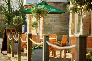 a table and chairs with an umbrella on a sidewalk at The Swan at Forest Row in Forest Row