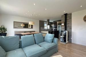 ein Wohnzimmer mit einem blauen Sofa und einer Küche in der Unterkunft Cosy Nature in Sainte-Pience