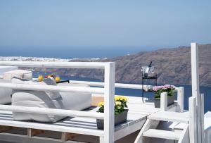 a white dock with chairs and flowers on the water at Saint Sin Suites - Adults Only in Imerovigli