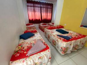 3 Betten in einem Zimmer mit roter Bettwäsche und blauen Kissen in der Unterkunft Santa clara palace hotel in Belém